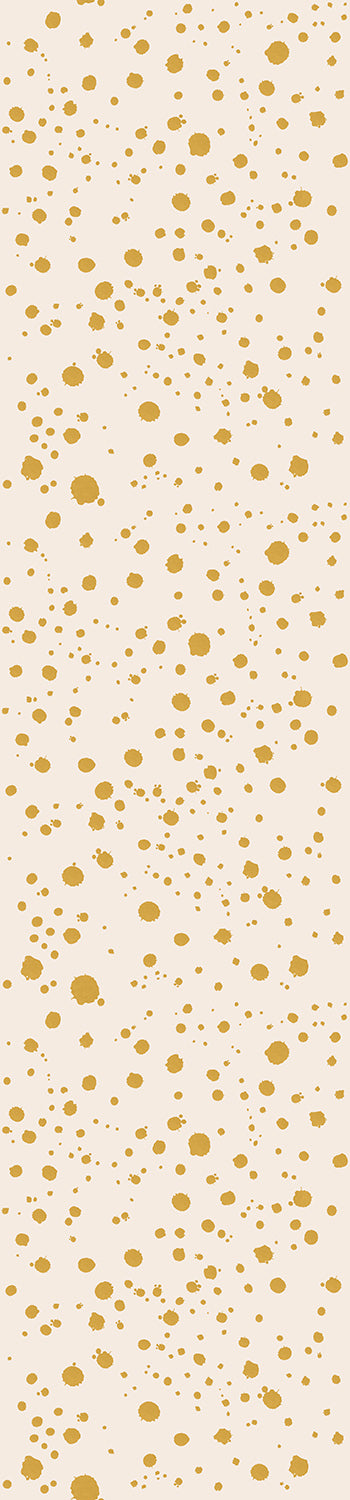 A roll of wallpaper with a mustard yellow ink drop pattern on a white background from drop it MODERN.