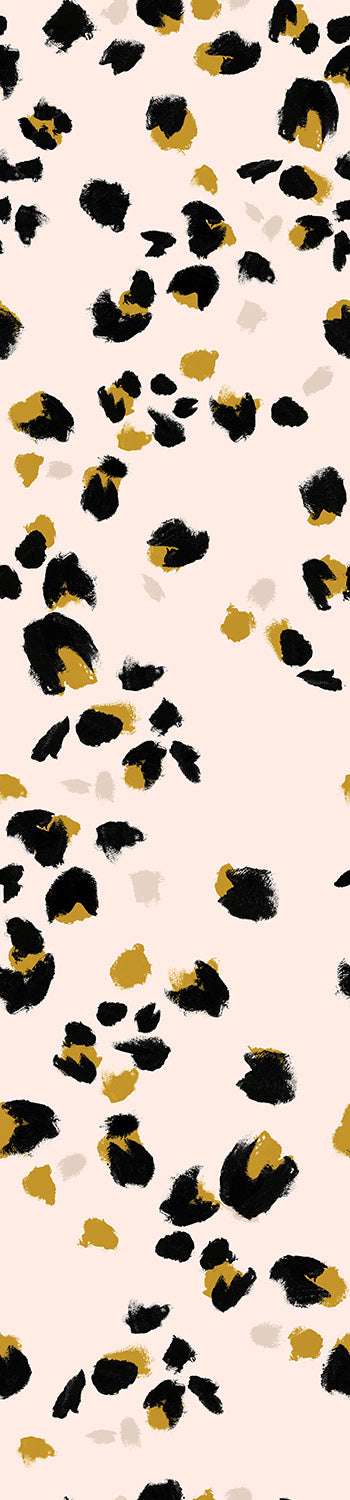 A roll of wallpaper featuring a pattern of stylized black and gold cat paw prints on a beige background from drop it MODERN.